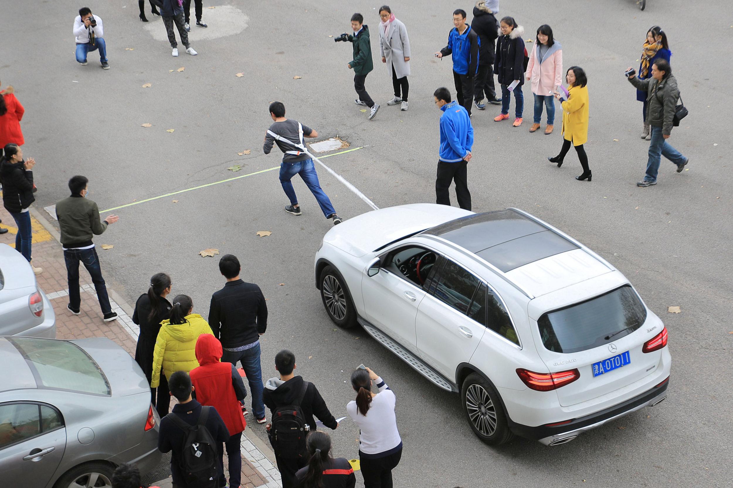 ↑11月20日，大学生在南开大学举行的拉汽车大赛中拖动汽车前行。CICPHOTO/王晓明 摄