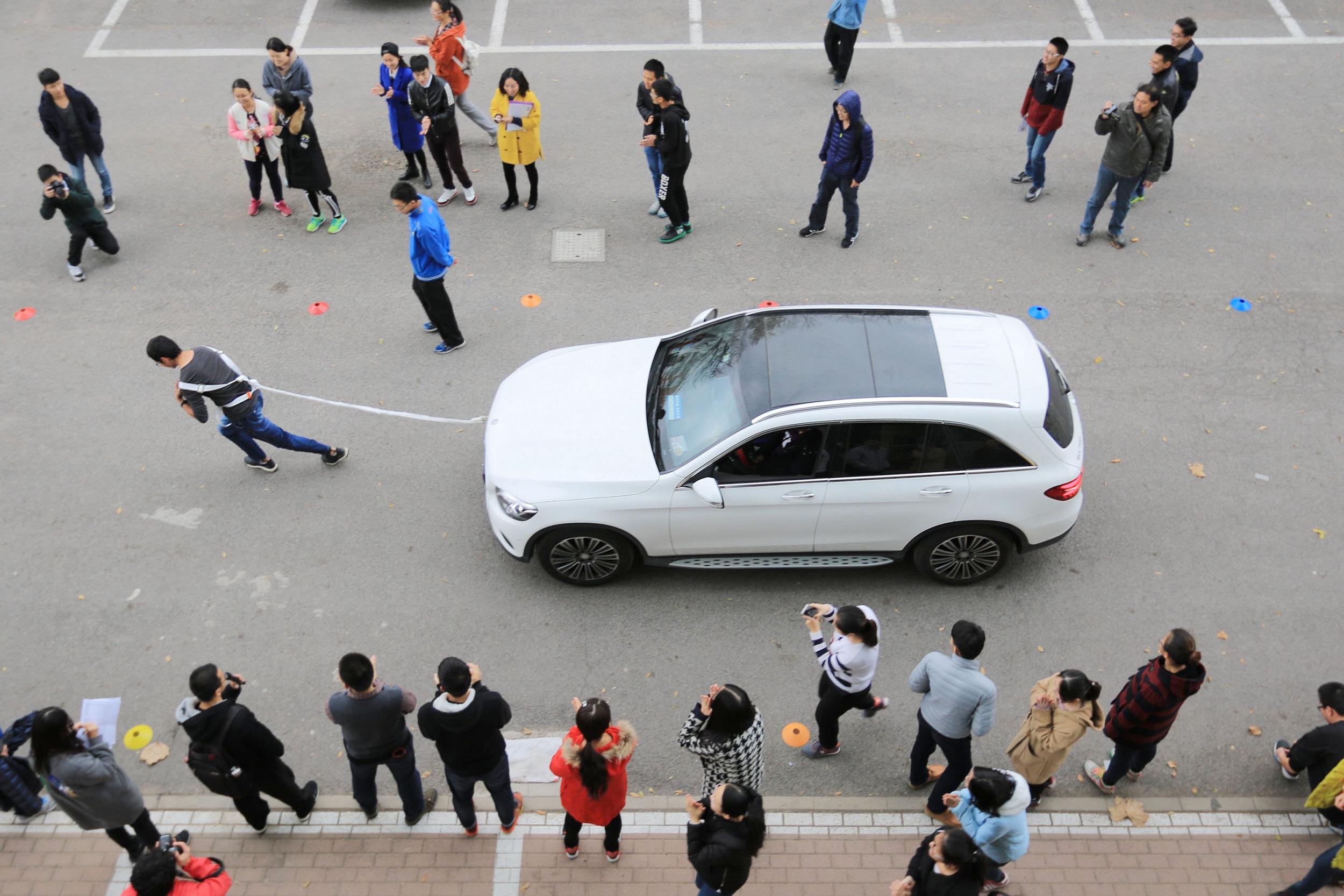 ↑11月20日，大学生在南开大学举行的拉汽车大赛中拖动汽车前行。CICPHOTO/王晓明 摄